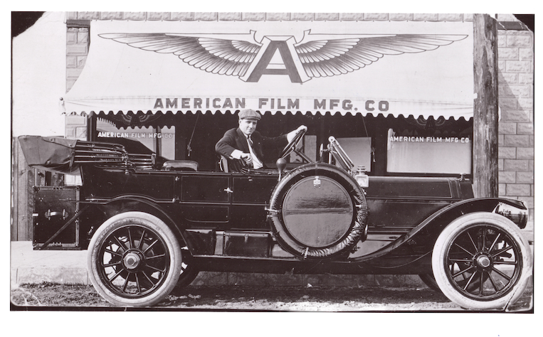 Movie director Allan Dwan sat in an open-top car in front of Flying A Studio north side La Mesa Blvd east of Palm Ave.